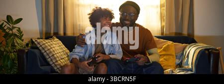 Father and Son Smiling While Playing Video Games Stock Photo