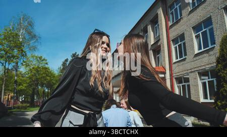 Two high school friends sharing a sweet kiss on the cheek to celebrate their affection and friendship Stock Photo