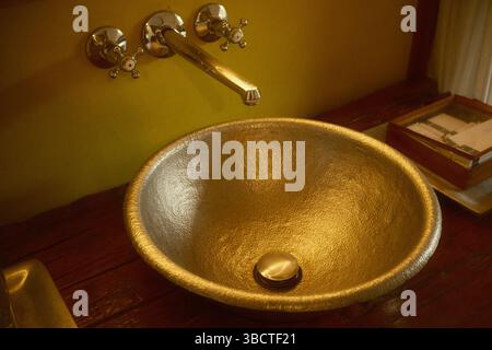 Elegant Metallic Wash Basin paired with a wall-mounted chrome faucet and wooden countertop Stock Photo
