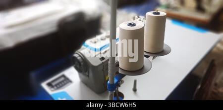 Close-up of two spools of white thread on a sewing machine, ready for use in a professional workshop Stock Photo