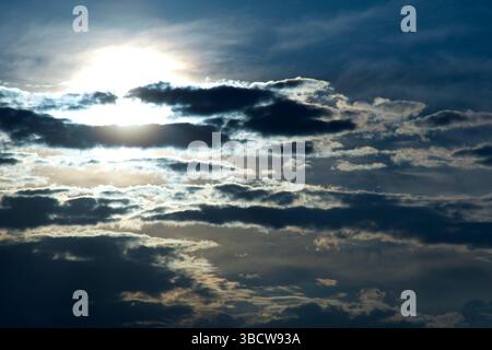 Sun pierces dramatic evening cloud layers. Stock Photo
