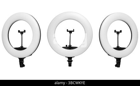 Three LED ring lights with smartphone holders arranged in a row on a white background. Stock Photo