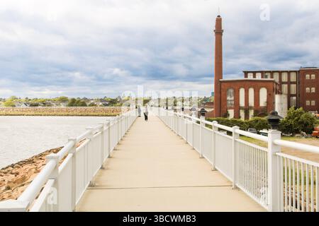 Covewalk's abandoned factories meet resilient hurricane dykes in New Bedford. A stark scene of decay, protection, and maritime history. Stock Photo