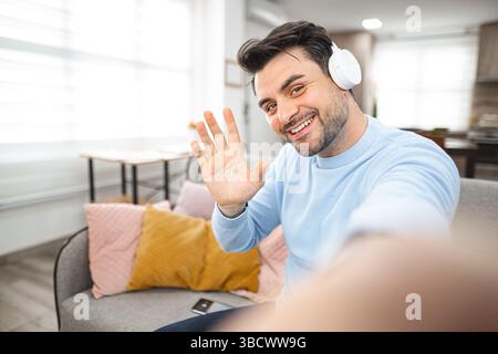 Selfie of brown-haired smiling man with white headphones Stock Photo