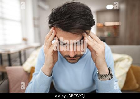 Depressed man sitting thoughtfully on couch Stock Photo
