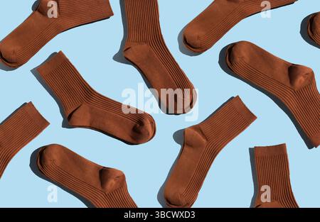 Brown socks arranged in playful pattern on a light blue background, showcasing texture and design, ideal for fashion and textile applications. Stock Photo