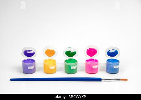 Open paint jars on a white background. Paint brush and water-based paints Stock Photo
