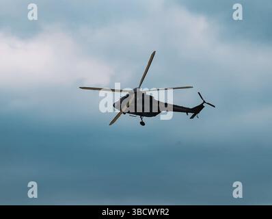Side View of a Military Helicopter in Flight Against a Turquoise Sky, Capturing the Details of the Aircraft's Profile and Creating a Dynamic Aviation Scene Stock Photo