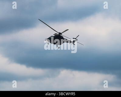 Side View of a Military Helicopter in Flight Against a Turquoise Sky, Capturing the Details of the Aircraft's Profile and Creating a Dynamic Aviation Scene. Stock photography Stock Photo