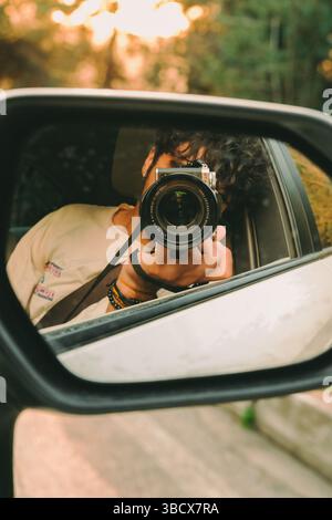 A photographer shooting himself in the car mirror Stock Photo