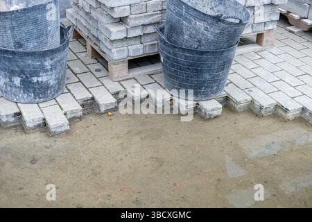 construction background stacked paving blocks and work buckets preparing ground for garden paver pathway construction Stock Photo