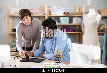 Two sewing workshop workers draw patterns on electronic tablet Stock Photo