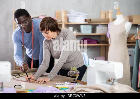 Two sewing workshop workers draw patterns on paper Stock Photo
