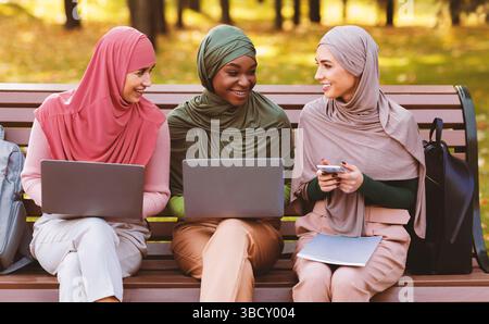 Muslim Female Students Using Laptops And Smartphone Learning Together Outside Stock Photo