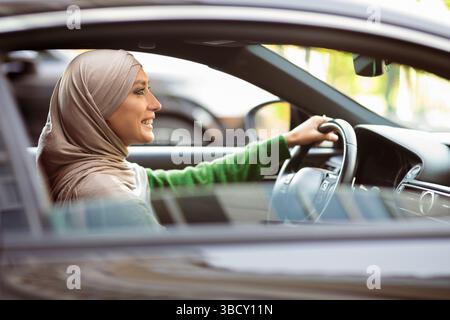 Cheerful muslim woman driving her new car Stock Photo