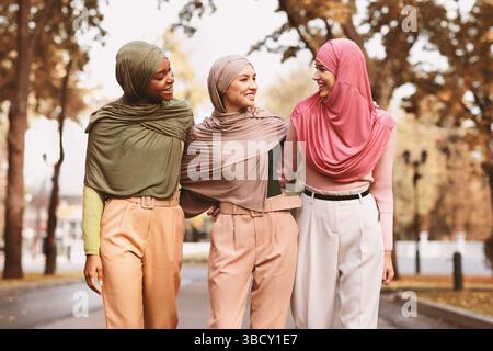Three Muslim Women Wearing Hijab And Modern Clothes Walking Outside Stock Photo