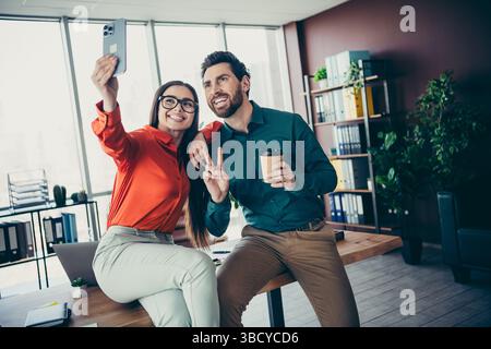 Professional coworkers enjoying a moment of leisure while taking a selfie in a modern office workspace Stock Photo