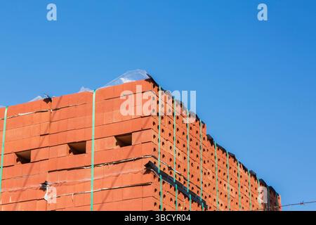 Close-up of tied bundles of neatly stacked red clay construction bricks in outdoor storage yard in spring. Stock Photo