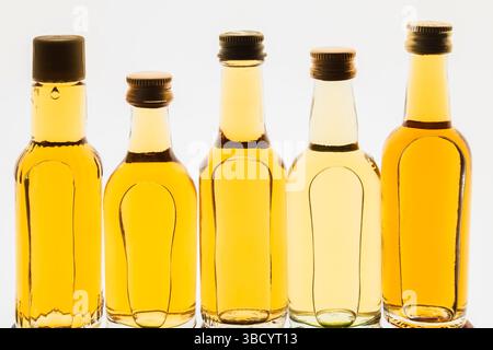 Upright miniature size golden liquor bottles on white translucent background. Stock Photo