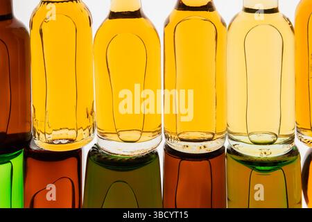 Two rows of colourful assorted shaped miniature size liquor bottles laid flat on white translucent background. Stock Photo