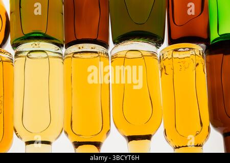Two rows of colourful assorted shaped miniature size liquor bottles laid flat on white translucent background. Stock Photo