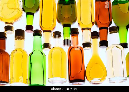 Two rows of colourful assorted shaped miniature size liquor bottles laid flat on white translucent background. Stock Photo