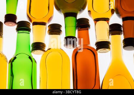 Two rows of colourful assorted shaped miniature size liquor bottles laid flat on white translucent background. Stock Photo