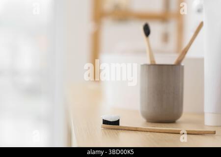 Bamboo tooth brush with applied tooth paste on table in bathroom Stock Photo