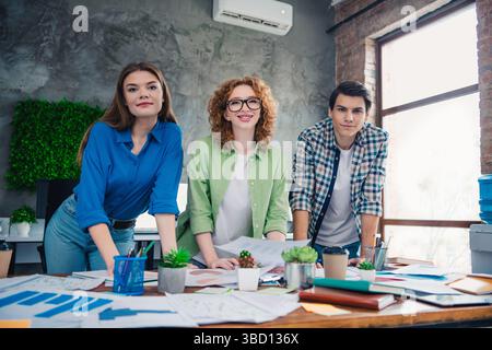 A group of three young professionals collaborating in a modern office space while working on creative team projects Stock Photo