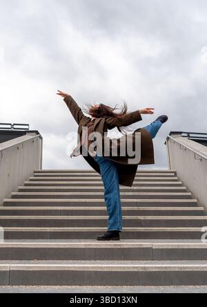 Ballerina performing elegant moves on concrete stairs in Stuttgart city Stock Photo