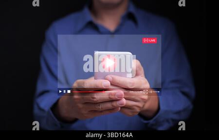 Watching online video is now embedded in everyday life. A man watches a video, live streaming, from his smartphone for entertainment, including stream Stock Photo