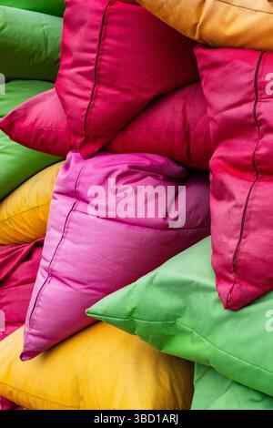 Pile of colorful beanbags and pillows stacked on top of each other. The pillows are of different colors and sizes, creating a vibrant and lively atmos Stock Photo