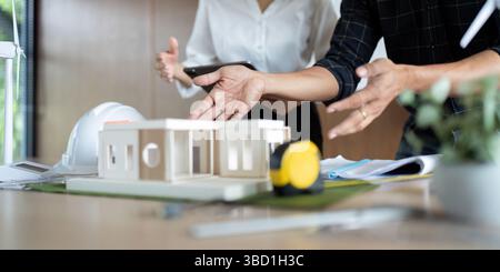 Sustainability and Engineering. Engineers collaborating on sustainable project models in a modern workspace. Stock Photo