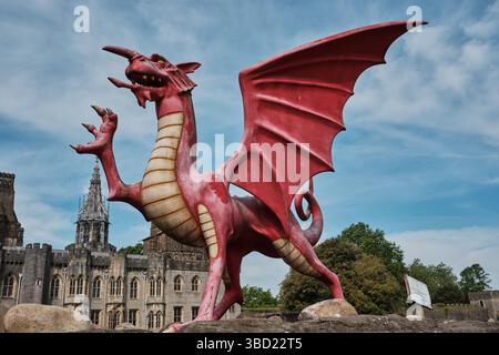 A striking red Welsh dragon sculpture outside Cardiff Castle in Wales, symbolising national pride against a backdrop of historic architecture. Stock Photo