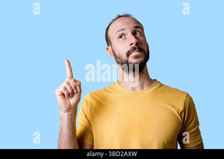 young man pointing finger up to copy space, having an idea Stock Photo