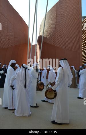 Expo Milano 2015. UAE pavilion view with sand dunes imitation and desert style walls. Group of men dancers with drums and white traditional dresses. Stock Photo