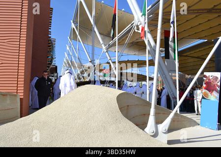 Expo Milano 2015. UAE pavilion view with sand dunes imitation and desert style walls. Group of Arab dancers in white dresses dancing. Decumano street. Stock Photo