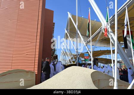 Expo Milano 2015. UAE pavilion view with sand dunes imitation and desert style walls. Group of Arab dancers in white dresses dancing. Decumano street. Stock Photo
