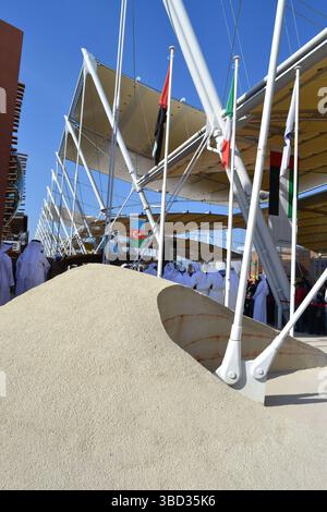 Expo Milano 2015. UAE pavilion view with sand dunes imitation and desert style walls. Group of Arab dancers in white dresses dancing. Decumano street. Stock Photo