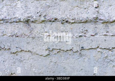 Close up of a concrete wall revealing cracks, erosion, and embedded pebbles, showcasing the effects of time and weather Stock Photo