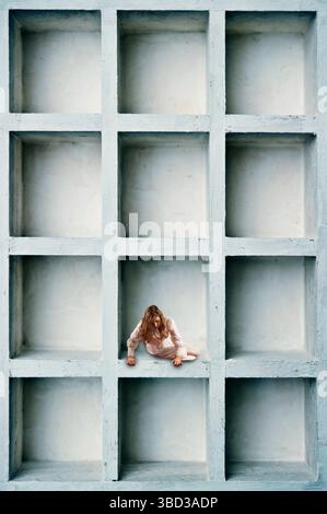 girl inside a box with compartments, looking down Stock Photo