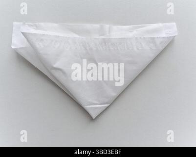 A white paper is folded into a triangle. The paper is white and has a pattern on it Stock Photo