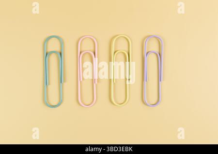 Top view of colorful paperclips on yellow background. School, office wallpaper. Flat lay, copy space. Stock Photo