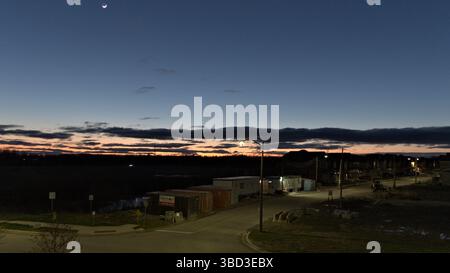 A beautiful sunset with a large moon in the sky. The sky is filled with clouds and the sun is setting. The scene is peaceful and serene Stock Photo