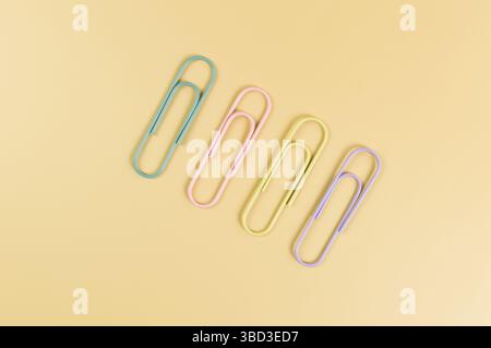 Top view of colorful paperclips on yellow background. School, office wallpaper. Flat lay, copy space. Stock Photo