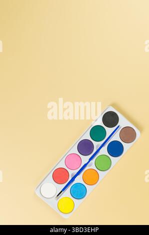 Top view of watercolor and paint brush on yellow background. Painting, art, copy space, flat lay. Stock Photo