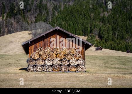 Wooden barn with firewood piles seen in the alps of Bavaria Stock Photo