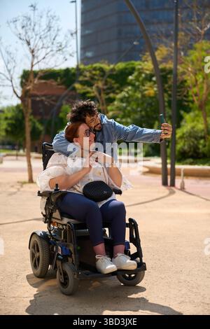 Young man taking selfie with friend in wheelchair - wheelchair and disability concept Stock Photo