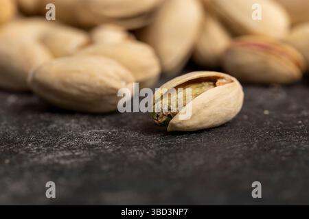 cracked pistachios with green nuts inside, the salted pistachios on the table are more delicious, piled together, side view Stock Photo