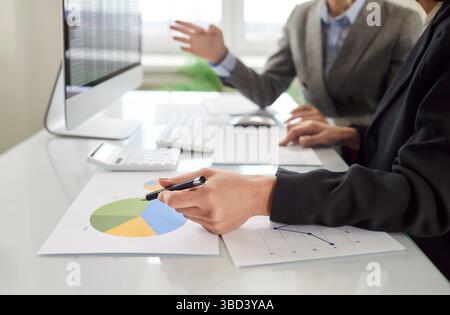 Two female colleagues working together, analyzing financial charts and discussing business results. Stock Photo